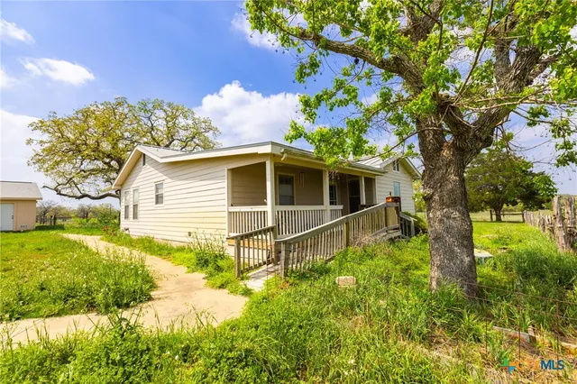 a white house with a big yard and large trees