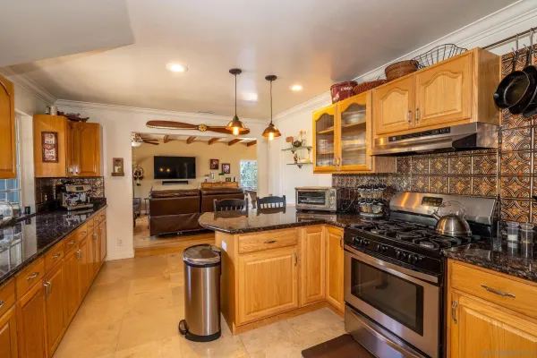 a large kitchen with stainless steel appliances wooden floor and a large window