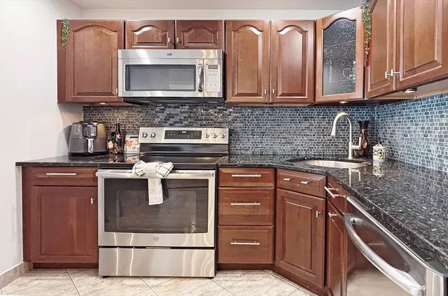 a kitchen with granite countertop a stove top oven microwave and cabinets