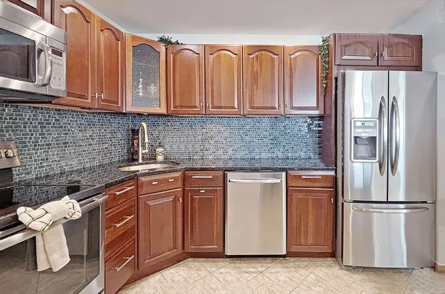 a kitchen with stainless steel appliances granite countertop a refrigerator a stove a sink and dishwasher