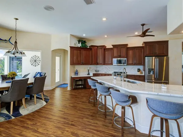 a kitchen with stainless steel appliances granite countertop a table chairs sink refrigerator and cabinets