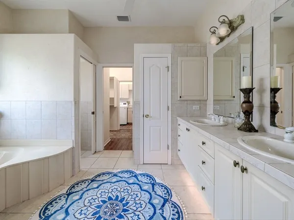 a spacious bathroom with a tub sink and mirror