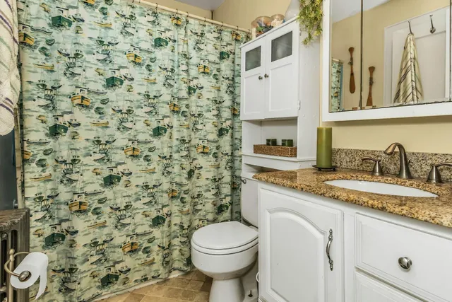 a bathroom with a granite countertop toilet sink and mirror