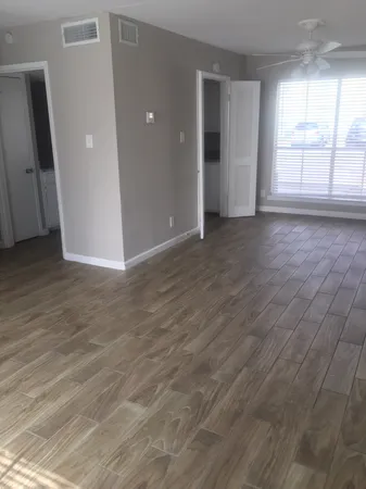 an empty room with wooden floor and windows