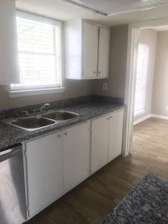 a kitchen with granite countertop a sink and white cabinets