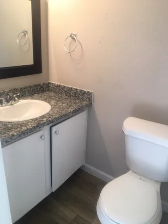 a bathroom with a granite countertop toilet sink and mirror