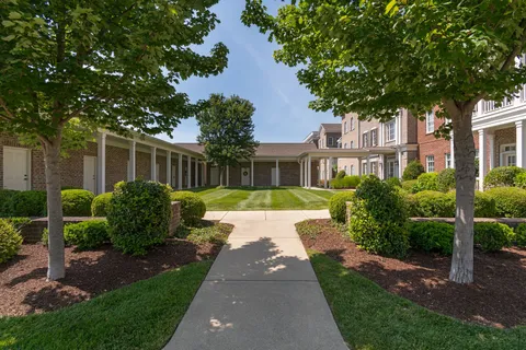 a view of a house with a small yard plants and large trees