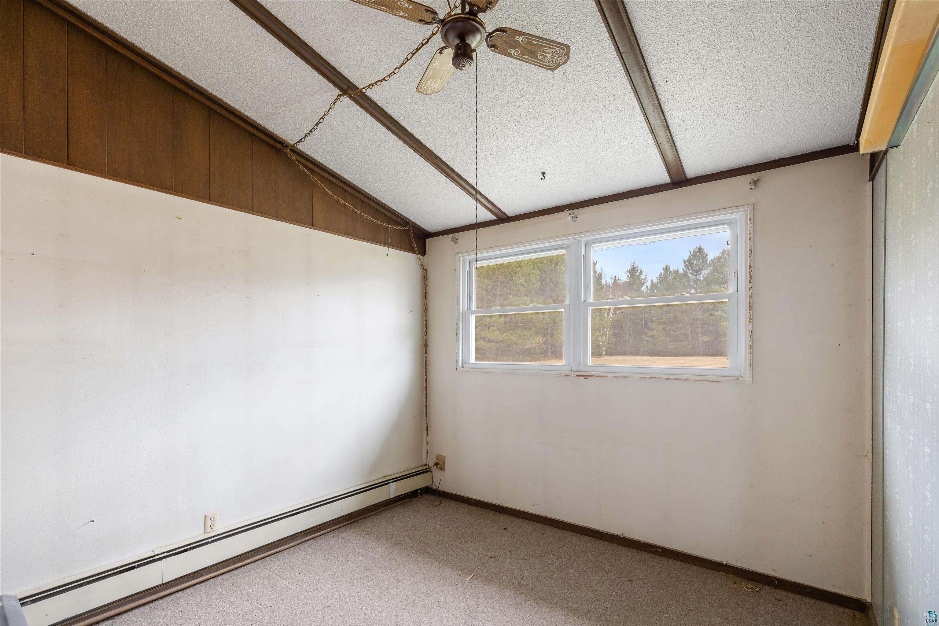 11574 Town Line Road Hibbing, MN 55746 - Photo 15 of 41 Room featuring a sloped ceiling with exposed beams, wood-finish paneling, and two white-framed windows providing natural illumination
