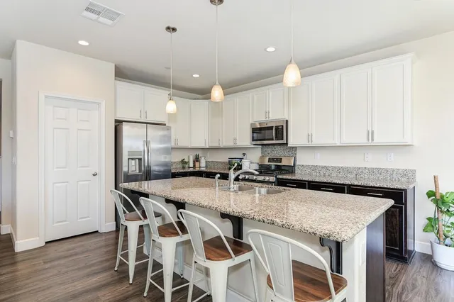 a kitchen with granite countertop a table chairs microwave and cabinets