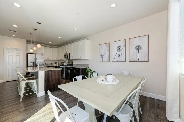 a kitchen with a dining table chairs refrigerator and white cabinets