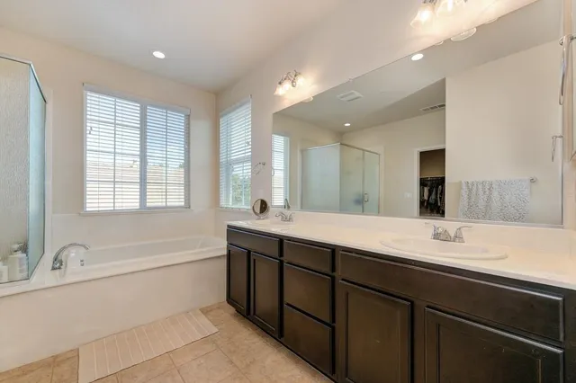 a spacious bathroom with a double vanity sink large mirror and a bathtub