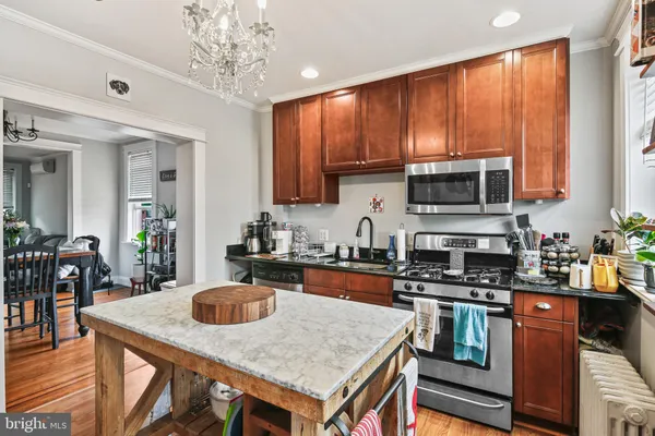 a kitchen with stainless steel appliances granite countertop a stove top oven a sink a dining table and chairs