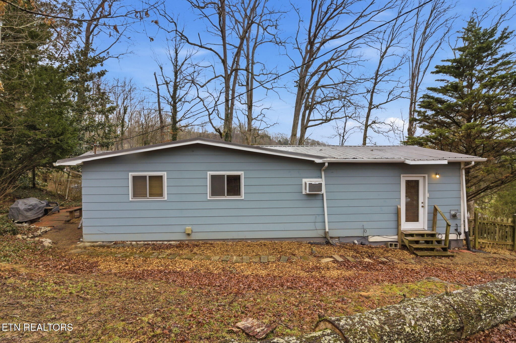 353 East Wolf Valley Road Heiskell, TN 37754 - Photo 31 of 34 a backyard of a house with large trees and brick wall