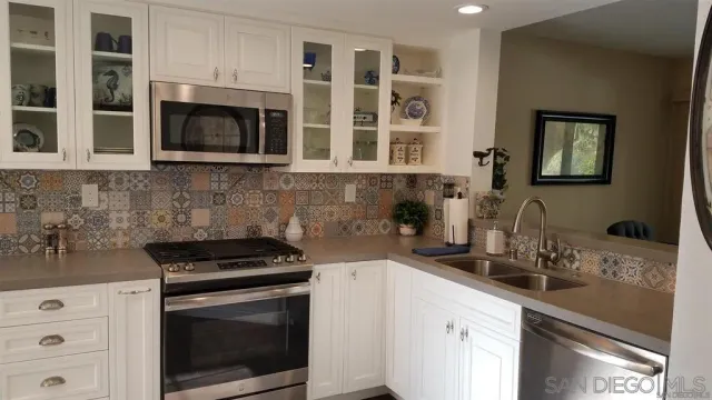 a kitchen with stainless steel appliances a stove microwave and sink