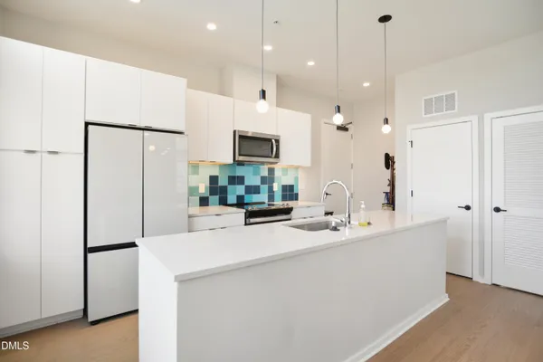 a kitchen with stainless steel appliances a refrigerator sink and white cabinets