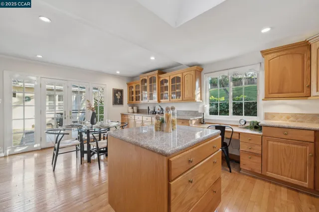 a kitchen with stainless steel appliances granite countertop wooden cabinets a sink a stove a dining table and chairs