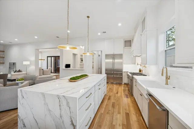 a kitchen with stainless steel appliances granite countertop a sink and a wooden floor