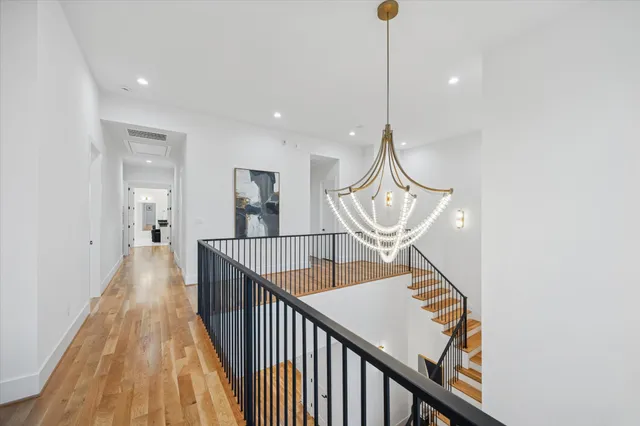 a view of a hallway with wooden floor and stairs