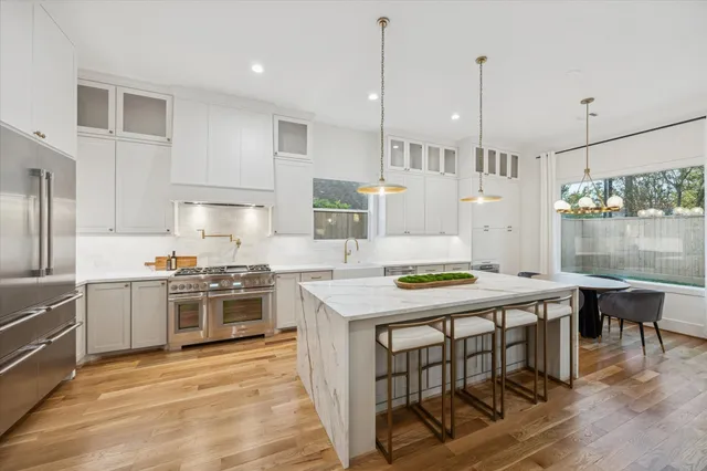 a kitchen with kitchen island a stove a table a sink refrigerator and cabinets