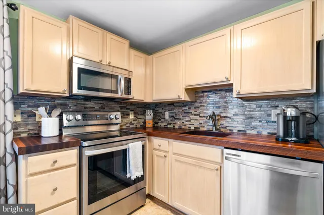 a kitchen with stainless steel appliances granite countertop a sink a stove a microwave refrigerator and cabinets
