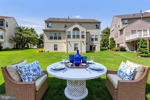 a view of a white house with a swimming pool and a yard table and chairs