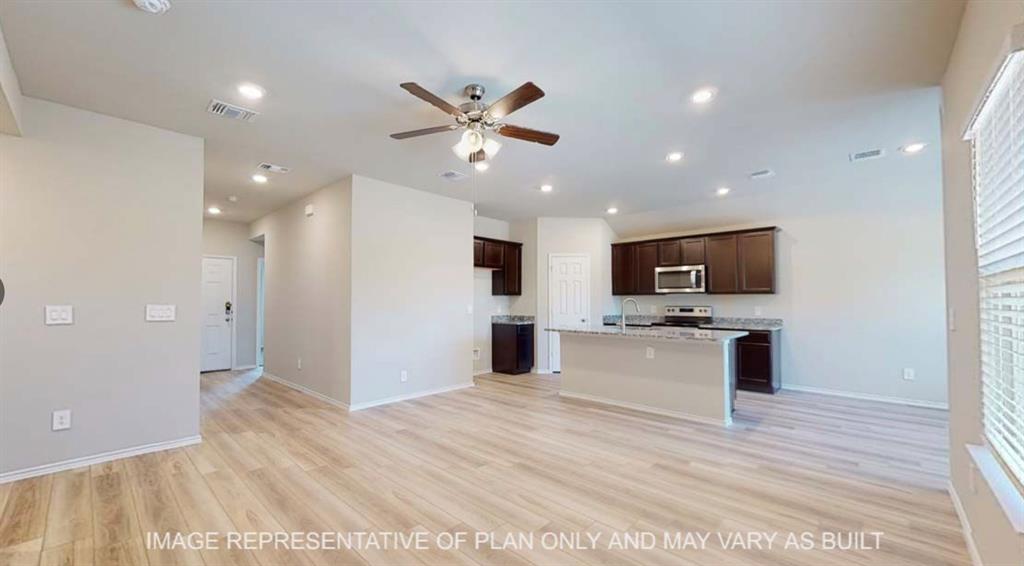 10212 Neptune Court Waco, TX 76708 - Photo 19 of 22 Kitchen with open floor plan, dark wood finish cabinets, a ceiling fan, a kitchen island with sink, and light wood-style flooring