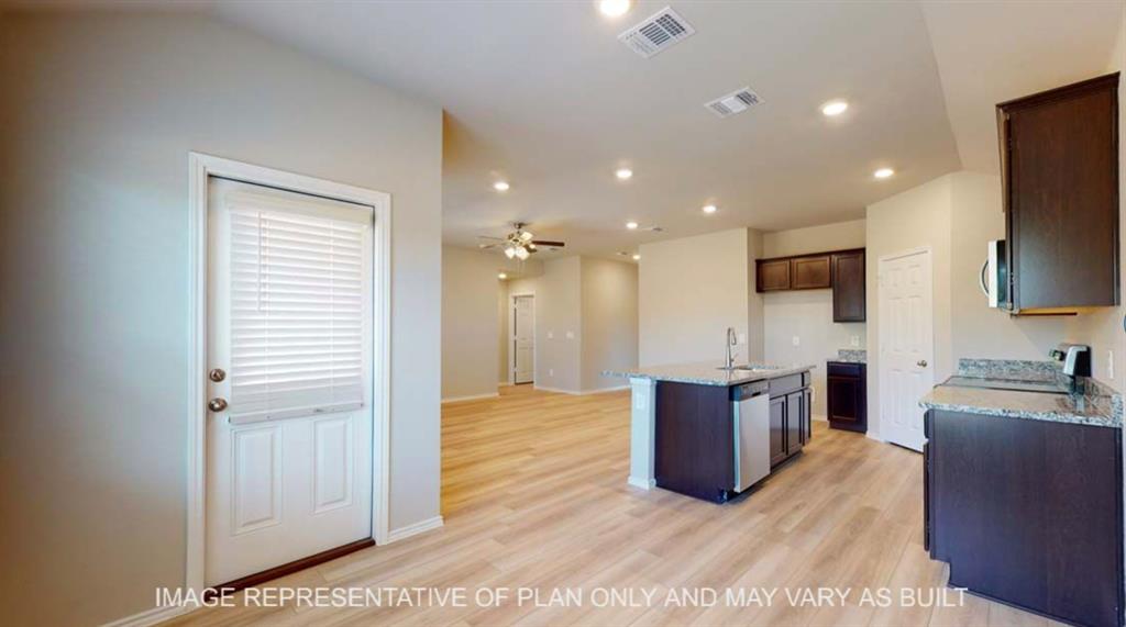 10212 Neptune Court Waco, TX 76708 - Photo 20 of 22 Kitchen with dark wood finish cabinetry, open floor plan, an island with sink, light wood-type flooring, and light stone counters