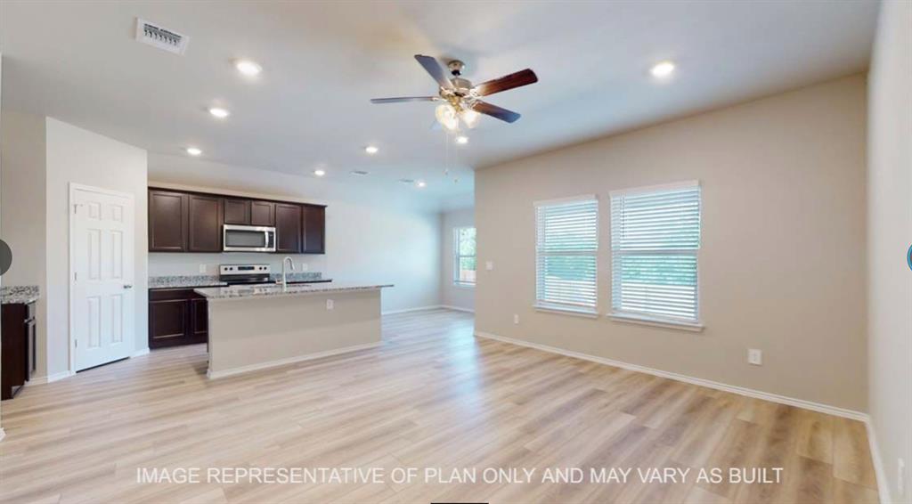 10212 Neptune Court Waco, TX 76708 - Photo 21 of 22 Kitchen with dark wood finish cabinets, open floor plan, a ceiling fan, a center island with sink, and light wood-style floors
