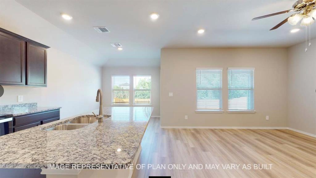 10212 Neptune Court Waco, TX 76708 - Photo 7 of 22 Kitchen with light stone countertops, dark wood finish cabinetry, light wood finished floors, a ceiling fan, and an island with sink