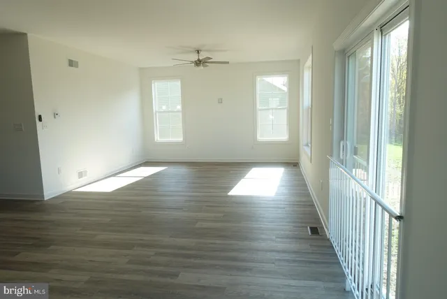 an empty room with windows and fan
