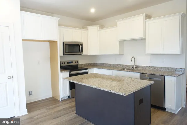a kitchen with granite countertop a sink and a stove top oven with wooden floor
