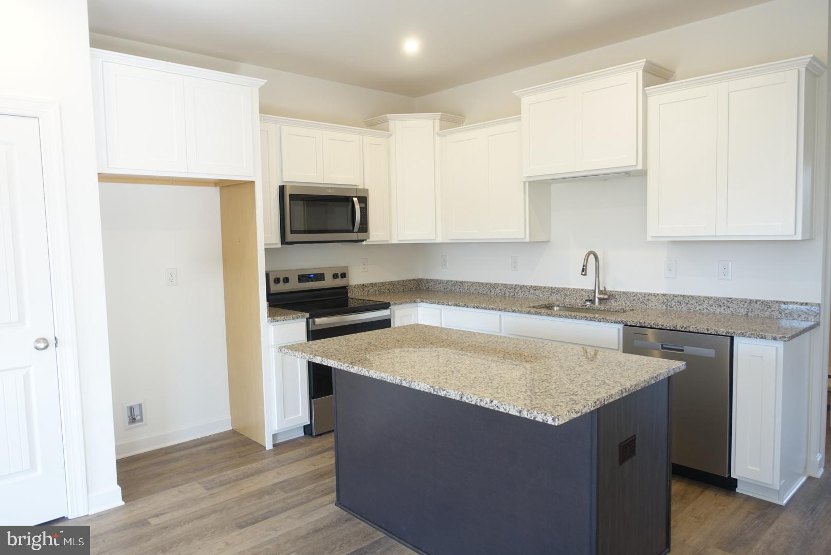 201 Kinneman Road, Unit 25 Abbottstown, PA 17301 - Photo 3 of 32 a kitchen with granite countertop a sink and a stove top oven with wooden floor