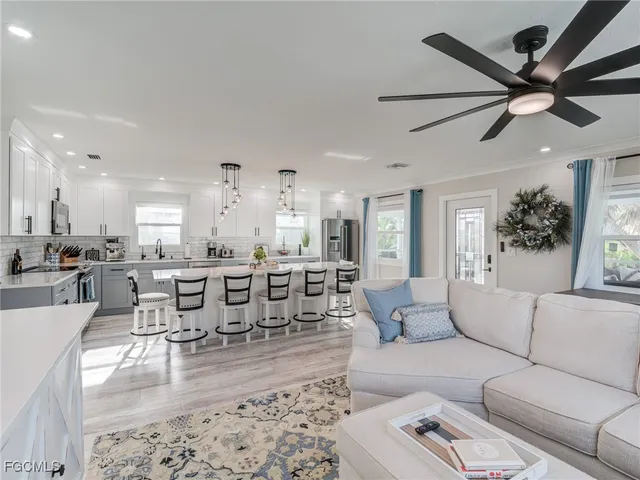 a living room with furniture kitchen view and a large window