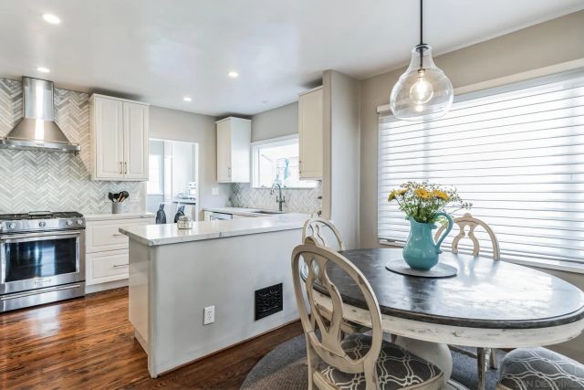 a kitchen with stainless steel appliances kitchen island granite countertop a stove a sink a dining table and chairs