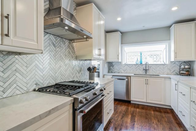 a kitchen with a stove a sink and wooden floor