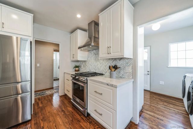 a kitchen with stainless steel appliances granite countertop a refrigerator a stove and a wooden floors