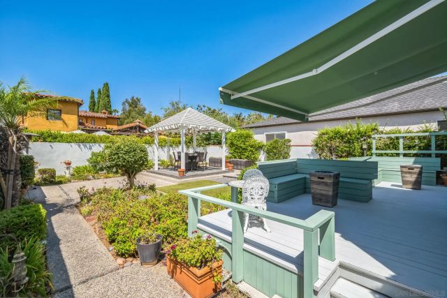 a view of a patio with couches table and chairs under an umbrella