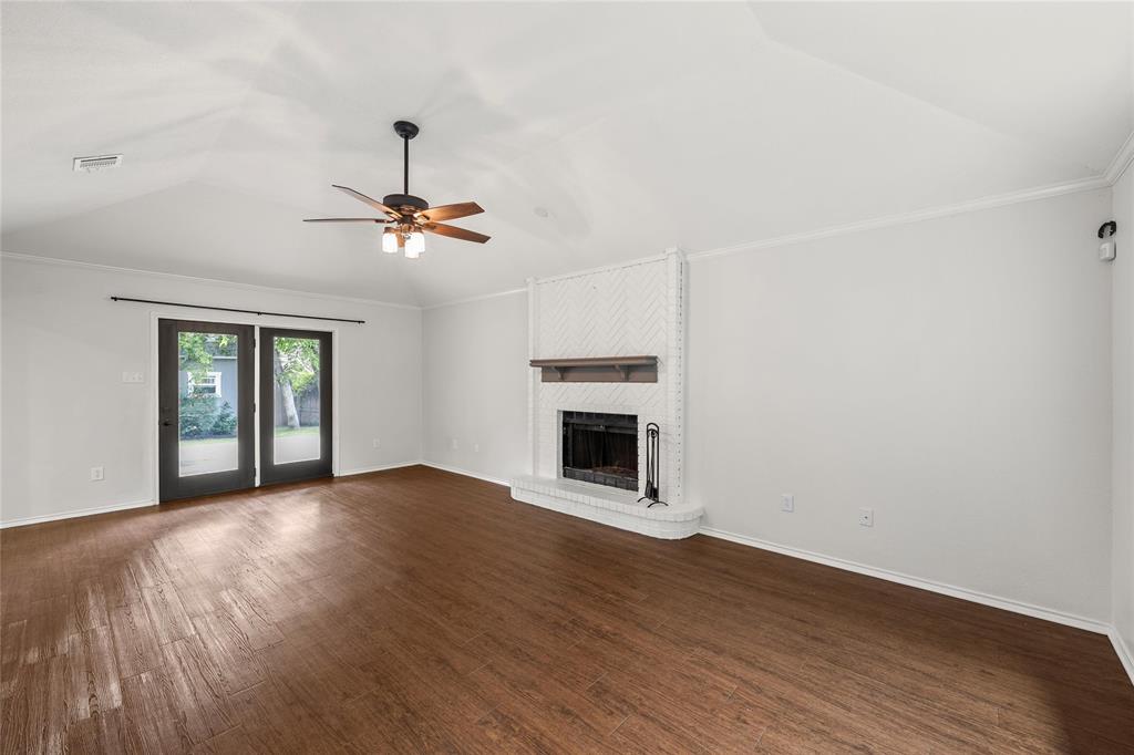 310 Ruth Drive Hewitt, TX 76643 - Photo 4 of 25 Living area featuring a vaulted ceiling with a ceiling fan, wood-finish flooring, a white brick fireplace with a wood mantel, and double glass-paneled doors