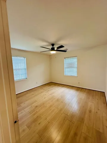 an empty room with wooden floor cabinet and windows