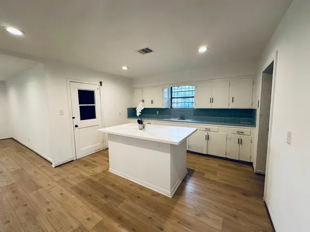 a large white kitchen with wooden floor and a sink