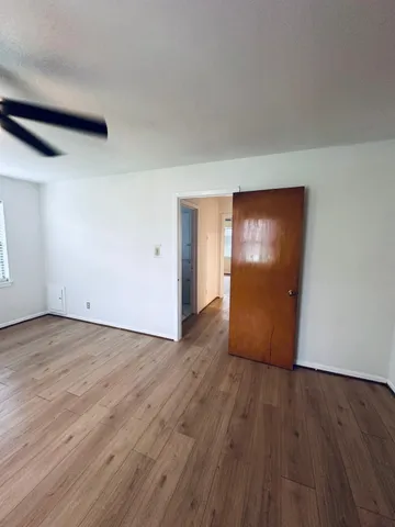 a view of an empty room with wooden floor and closet