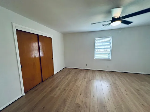an empty room with wooden floor cabinet and windows