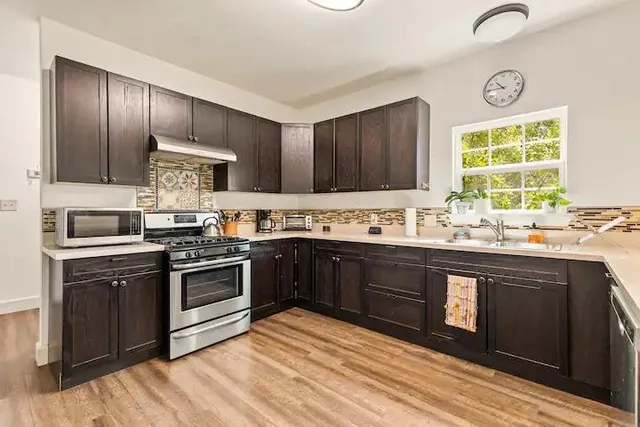 a kitchen with stainless steel appliances granite countertop a stove sink and cabinets