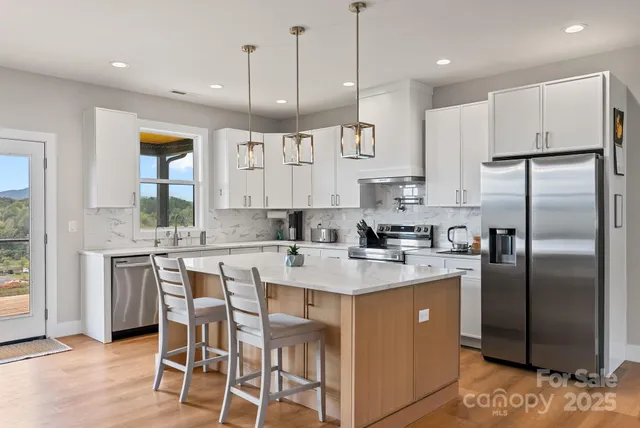 a kitchen with stainless steel appliances granite countertop a refrigerator a sink a stove a dining table and chairs