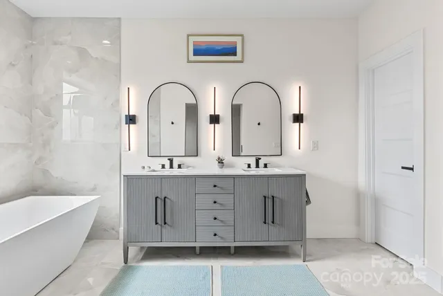 a bathroom with double vanity sink a two mirror a bathtub and next to a window
