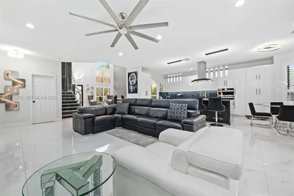 a living room with furniture kitchen view and a chandelier