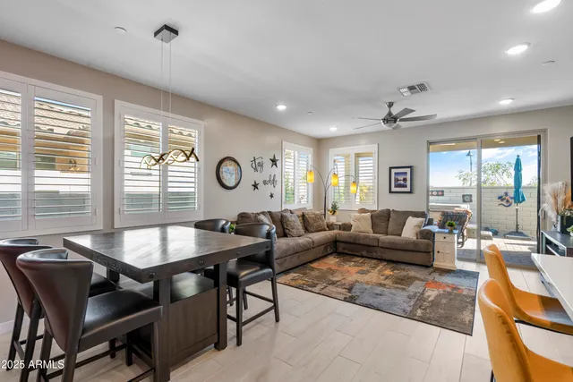 a kitchen with stainless steel appliances granite countertop a refrigerator a sink a stove and chairs with wooden floor