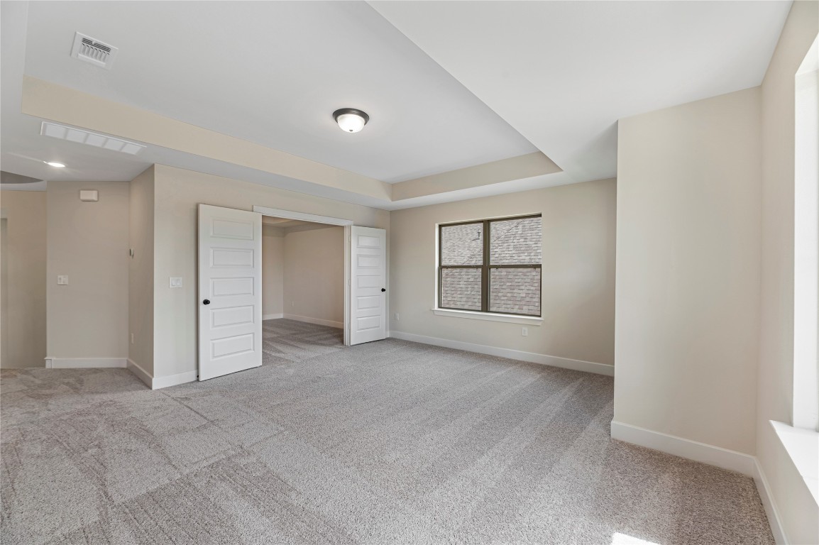 1508 Rodeo Ridge Drive Georgetown, TX 78628 - Photo 19 of 37 Unfurnished bedroom with light colored carpet and a tray ceiling
