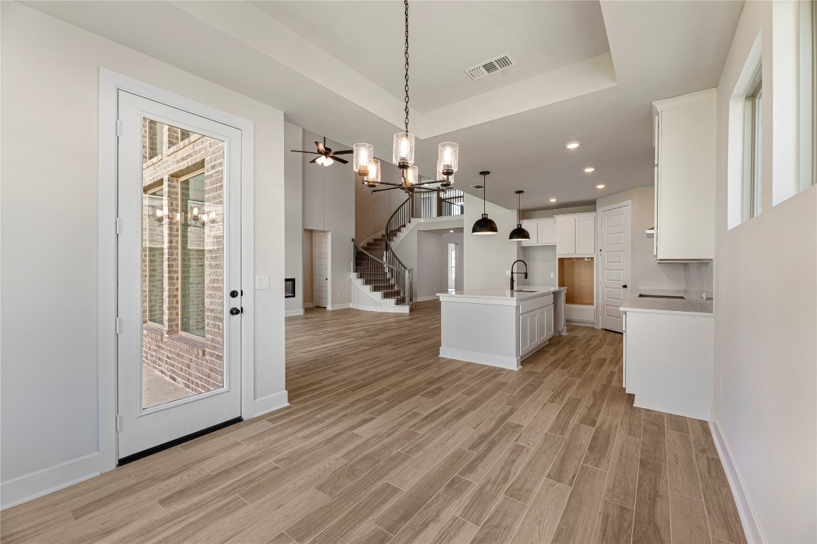 1508 Rodeo Ridge Drive Georgetown, TX 78628 - Photo 36 of 37 Kitchen featuring a chandelier, open floor plan, hanging light fixtures, a kitchen island with sink, and white cabinets