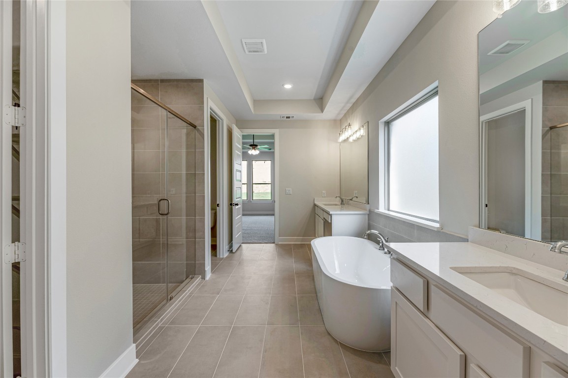 1508 Rodeo Ridge Drive Georgetown, TX 78628 - Photo 9 of 37 Bathroom with a shower stall, a freestanding bath, two vanities, light tile patterned floors, and ceiling fan